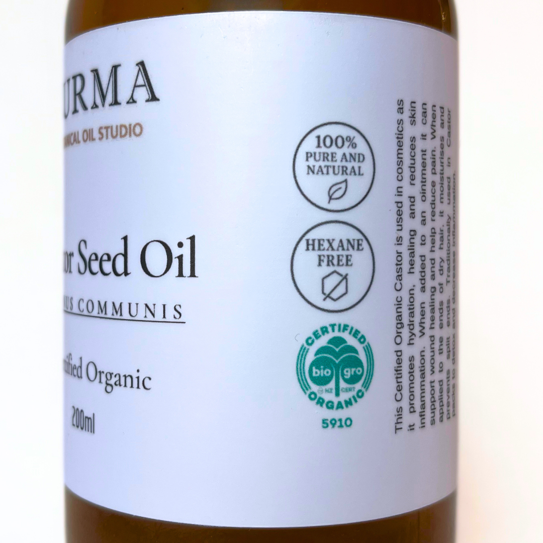 Bottle of castor seed oil with a label indicating purity and certification details.